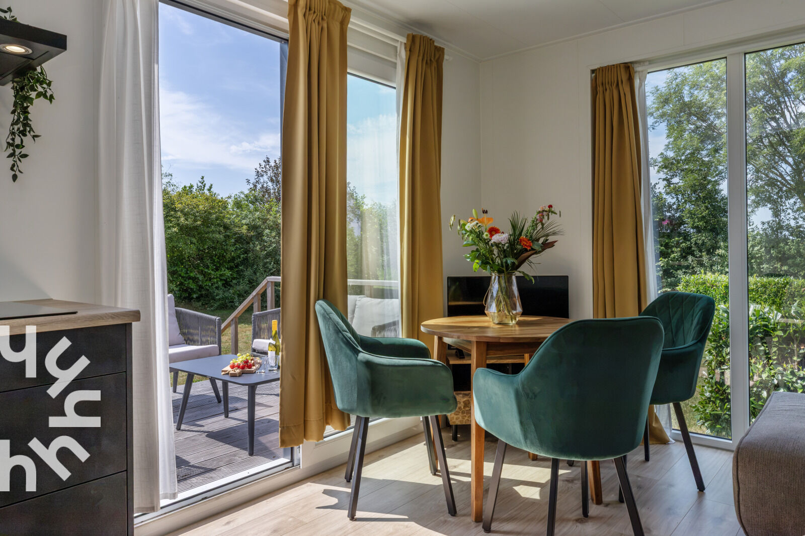 Esstisch mit grünen Stühlen und Blick in den Garten